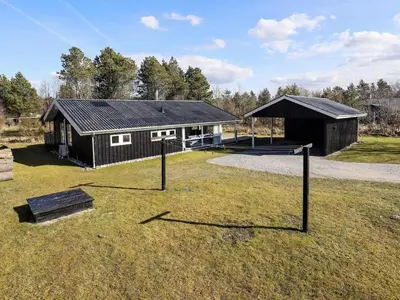 a small black building with a tennis court in front of it at 6 person holiday home in Blokhus in Blokhus