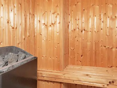 a wooden wall in a sauna with a box of rocks at 6 person holiday home in Blokhus-By Traum in Blokhus