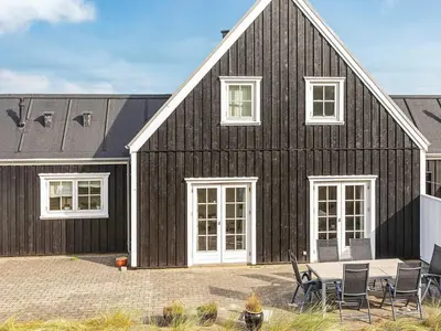 a black house with chairs and a table in front of it at 6 person holiday home in Blokhus-By Traum in Blokhus