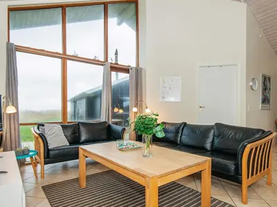 a living room with a black leather couch and a table at 8 person holiday home in Ulfborg in Thorsminde