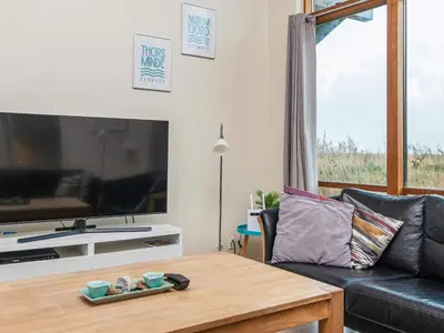a living room with a black couch and a table at 8 person holiday home in Ulfborg in Thorsminde