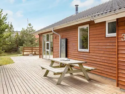 a picnic table on a deck next to a house at Luxury Eco Cottage in Klitmoller - By Traum Ferienwohnungen in Klitmøller