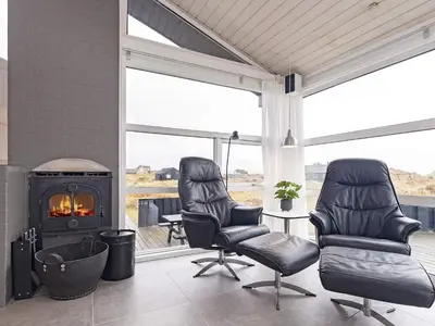 a living room with two chairs and a fireplace at Luxury Beachfront Retreat - By Traum Ferienwohnungen in Rødhus
