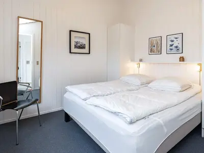 a bedroom with a large white bed and a chair at Luxury Beachfront Retreat - By Traum Ferienwohnungen in Rødhus