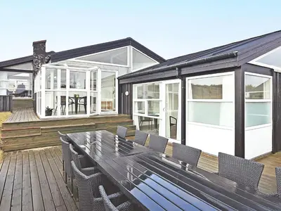 a patio with a table and chairs on a deck at Luxury Beachfront Retreat - By Traum Ferienwohnungen in Rødhus