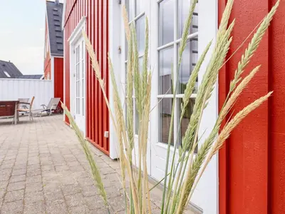 a house with red and white walls and tall grass at 6 person holiday home in Blokhus-By Traum in Blokhus