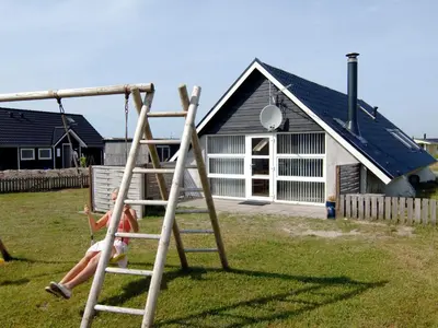 a woman sitting on a swing in front of a house at 6 person holiday home in Harboøre-By Traum in Harboør