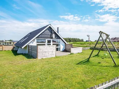 a small house with a pitched roof with a playground at 6 person holiday home in Harboøre-By Traum in Harboør