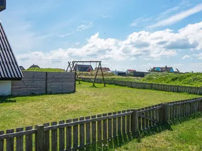 a wooden fence with a playground in a field at 6 person holiday home in Harboøre-By Traum in Harboør