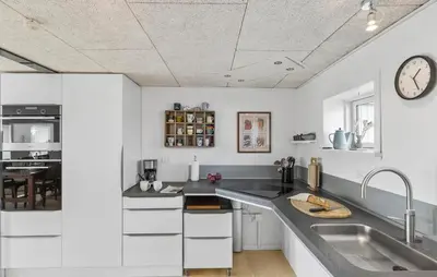 a kitchen with white cabinets and a clock on the ceiling at Cozy Home In Øster Assels With Wifi in Øster Assels