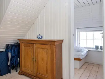 a bedroom with a wooden cabinet and a bed at 9 person holiday home in Harboøre-By Traum in Harboør