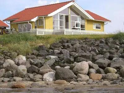 a yellow house with a bunch of rocks in front of it at 4 person holiday home in Vinderup-By Traum in Vinderup