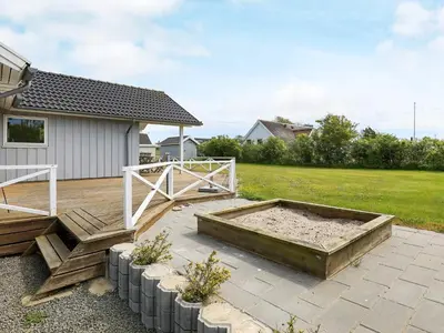 a backyard with a sandbox and a wooden deck at 8 person holiday home in Lemvig-By Traum in Lemvig