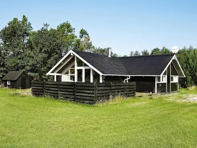 a house with a black roof in a field at Cozy Retreat with Spa - By Traum Ferienwohnungen in Stenbjerg