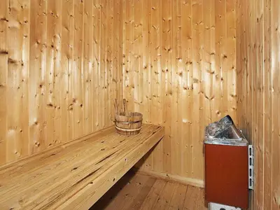 a wooden room with a bench and a trash can at Cozy Retreat with Spa - By Traum Ferienwohnungen in Stenbjerg
