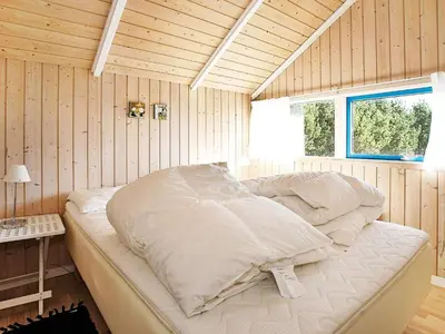 a large bed in a room with wooden walls at Cozy Retreat with Spa - By Traum Ferienwohnungen in Stenbjerg