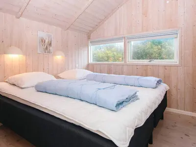 a large bed in a room with two windows at 8 person holiday home in Harboøre-By Traum in Harboør