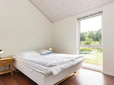 a white bedroom with a bed and a window at 8 person holiday home in Skals in Hjarbæk