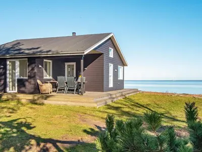a small house with a deck and a view of the water at 6 person holiday home in Harboøre-By Traum in Harboør