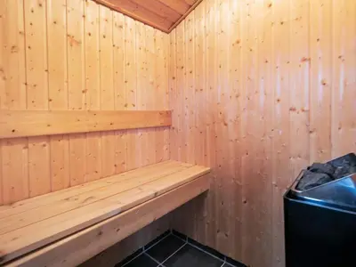 a wooden sauna with a bench and a stove at 8 person holiday home in Brovst-By Traum in Brovst