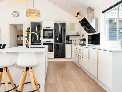 a kitchen with white cabinets and a black refrigerator at Luxury Retreat by the Sea - By Traum Ferienwohnungen in Harboør