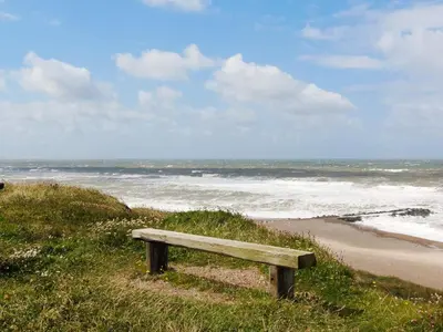a wooden bench sitting on the side of a beach at Luxury Retreat by the Sea - By Traum Ferienwohnungen in Harboør