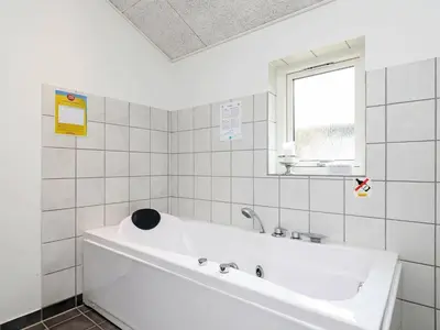 a white tub in a white tiled bathroom with a window at 10 person holiday home in Løgstør-By Traum in Trend