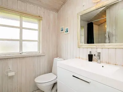 a bathroom with a toilet and a sink and a mirror at 6 person holiday home in Blokhus-By Traum in Blokhus