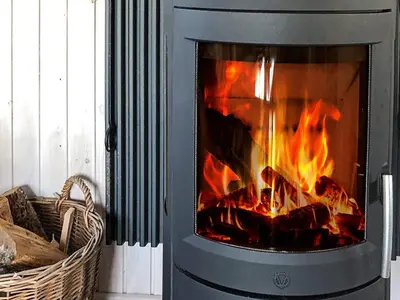 a stove with a fire in it next to a basket at 6 person holiday home in Blokhus-By Traum in Blokhus