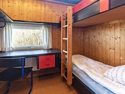 a bedroom with a desk and bunk beds in a room at 8 person holiday home in Vestervig in Vestervig