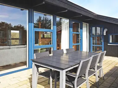 a wooden table and chairs on a patio at 8 person holiday home in Vestervig in Vestervig