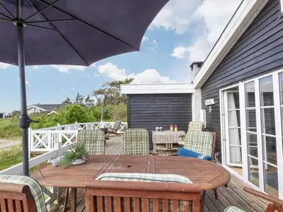 a wooden table with chairs and an umbrella on a deck at 8 person holiday home in Løgstør-By Traum in Trend