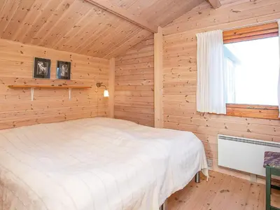a bedroom with a bed in a log cabin at Seaside Fun & Relaxation-By Traum in Harboør