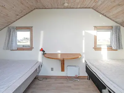 a small room with two beds and a wooden table at Seaside Fun & Relaxation-By Traum in Harboør
