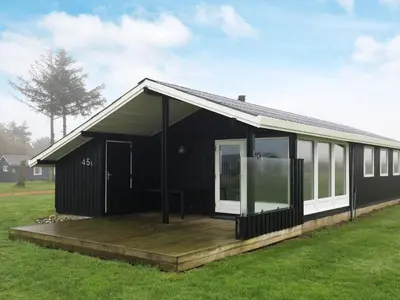 a black house with a wooden deck in a field at 6 person holiday home in Vinderup-By Traum in Vinderup