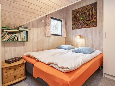 a large bed in a room with a wooden wall at 6 person holiday home in Roslev-By Traum in Vester Grønning
