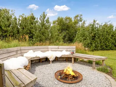 a fire pit with two wooden benches and a fire pit at Holiday Home Yngve - 3-5km from the sea by Interhome in Fjerritslev