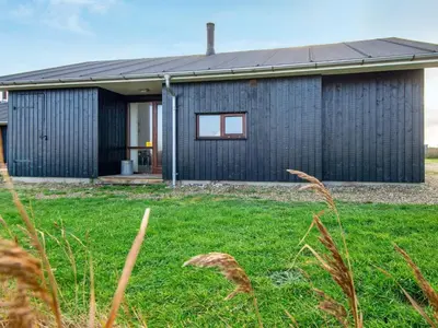 a black house with a green yard in front of it at 8 person holiday home in Ulfborg-By Traum in Thorsminde