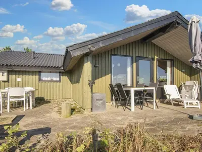 a green house with a table and chairs and a patio at 7 person holiday home in Lemvig-By Traum in Lemvig