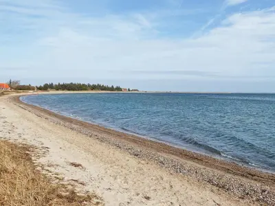 a beach with the ocean and trees in the distance at 7 person holiday home in Lemvig-By Traum in Lemvig