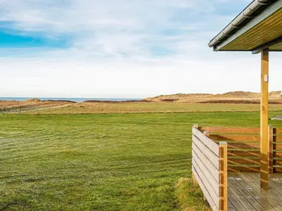 a house with a wooden fence in a field at 6 person holiday home in Lemvig-By Traum in Trans