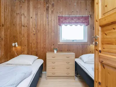 two beds in a room with wooden walls and a window at Cozy Renovated Cottage - By Traum Ferienwohnungen in Harboør