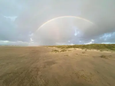 a rainbow in the sky over a sandy beach at 8 person holiday home in Pandrup-By Traum in Blokhus