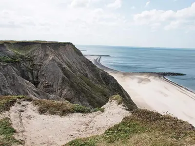 a sandy beach next to the ocean on a cliff at 4 person holiday home in Lemvig-By Traum in Trans