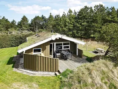 a small house with a deck in the grass at 6 person holiday home in Blokhus-By Traum in Blokhus
