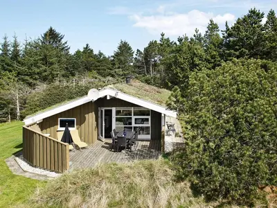 a small cabin with a deck in a field at 6 person holiday home in Blokhus-By Traum in Blokhus