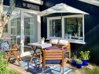 a table and chairs with an umbrella on a patio at 4 person holiday home in Blokhus-By Traum in Blokhus