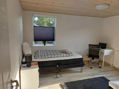 a bedroom with a bed and a desk and a window at Venos Home in Lemvig