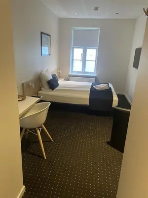 a small room with a bed and a window at Hotel Tante in Lemvig