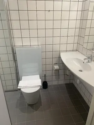 a white bathroom with a toilet and a sink at Hotel Tante in Lemvig